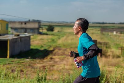 A man jogs in rural area wearing sportswear, emphasizing fitness and determination.